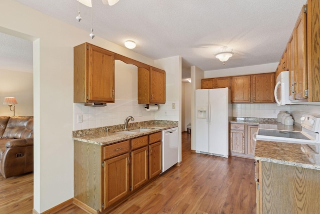 32 11th Ave S Unit 204, Hopkins, MN 55343 - kitchen featuring white appliances, a sink, wood finished floors, decorative backsplash, and a textured ceiling