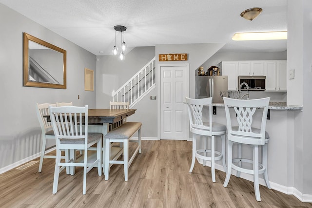1963 Bluestem Ln, Shoreview, MN 55126 - dining space featuring light wood-style flooring, baseboards, and stairs
