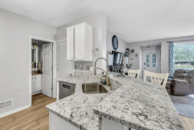 1963 Bluestem Ln, Shoreview, MN 55126 - kitchen featuring a sink, dishwasher, light wood-type flooring, white cabinetry, and a textured ceiling
