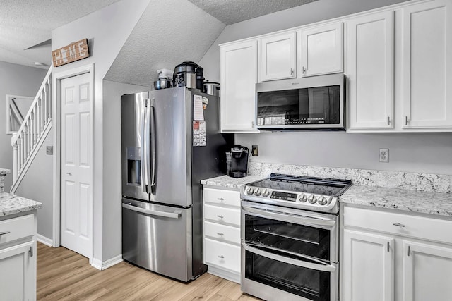 1963 Bluestem Ln, Shoreview, MN 55126 - kitchen featuring stainless steel appliances, light wood finished floors, white cabinets, a textured ceiling, and light stone countertops