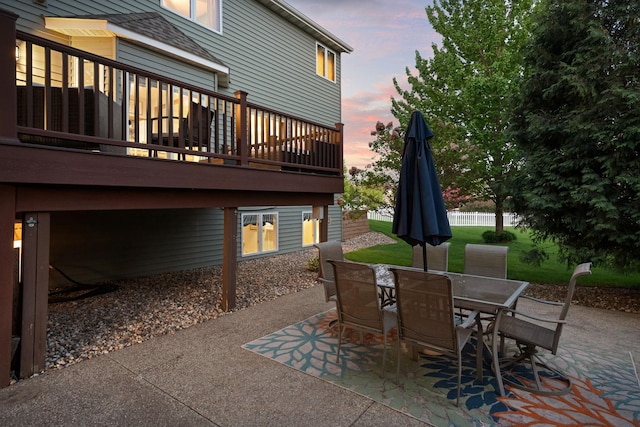 patio terrace at dusk with outdoor dining area and a deck