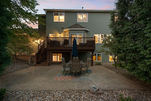 back of house at dusk with a patio, stairway, and a deck