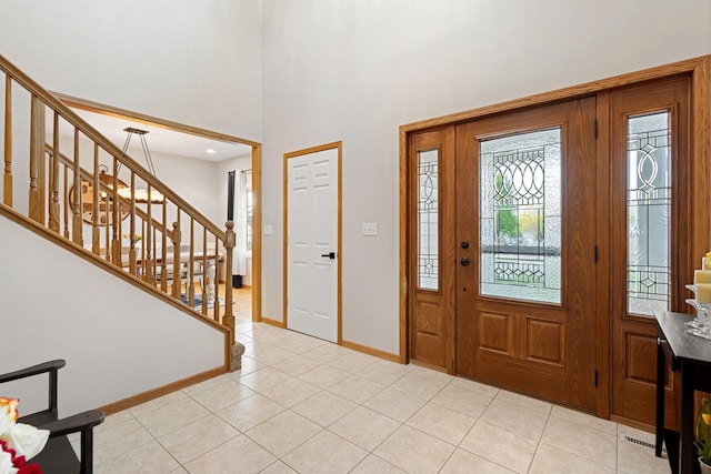 entryway featuring stairs, light tile patterned floors, baseboards, and a towering ceiling