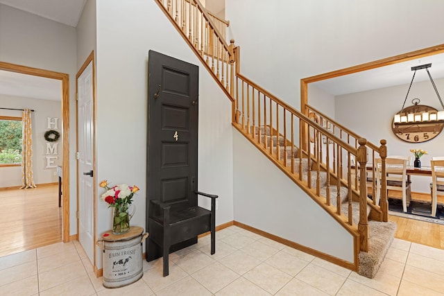 stairs featuring tile patterned flooring, baseboards, and a high ceiling