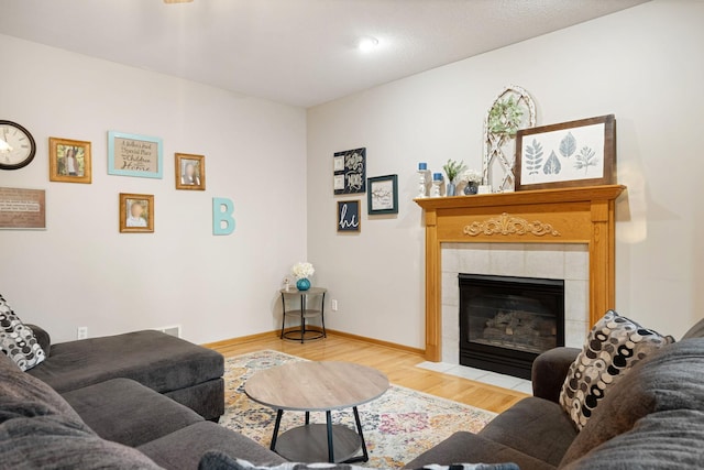 living area with wood finished floors, a fireplace, and baseboards
