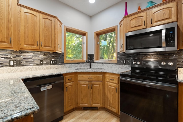 kitchen with stainless steel microwave, dishwasher, black range with electric cooktop, a sink, and light wood-style flooring