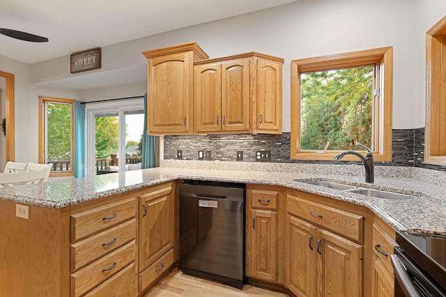 kitchen featuring dishwasher, a sink, light stone countertops, a peninsula, and decorative backsplash
