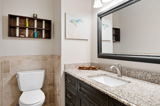 bathroom with toilet, tile walls, and vanity