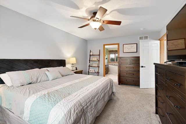 bedroom featuring light carpet, a ceiling fan, and ensuite bath