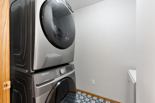 laundry room with estacked washer and dryer and baseboards