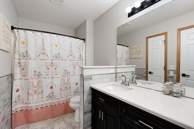 full bath with toilet, vanity, tile walls, and a shower with curtain