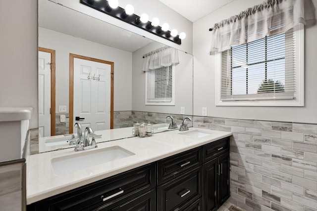 full bath featuring tile walls, double vanity, and a wainscoted wall