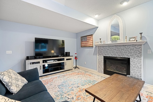 living room featuring baseboards, wood finished floors, a fireplace, and a textured ceiling