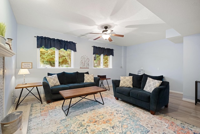 living area featuring wood finished floors, ceiling fan, and baseboards