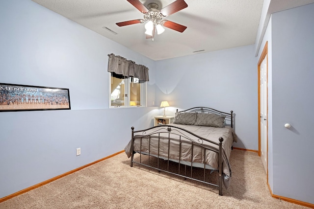 carpeted bedroom featuring baseboards, a textured ceiling, and a ceiling fan