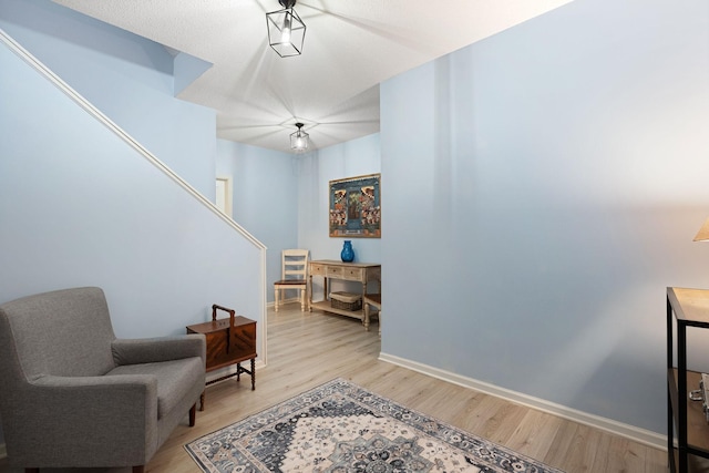 sitting room featuring light wood-type flooring, baseboards, and stairway