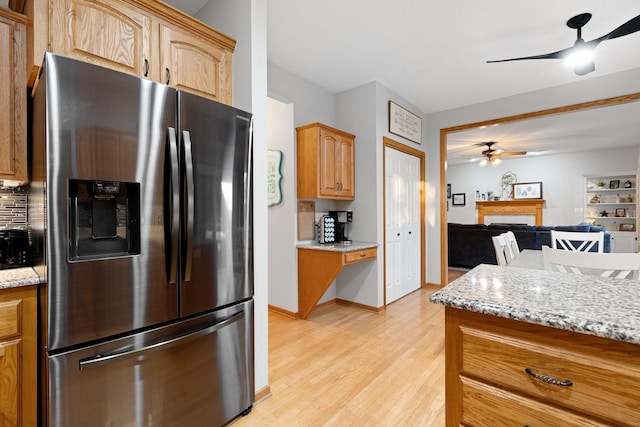 2703 10th Ave SW, Austin, MN 55912 - kitchen featuring stainless steel fridge with ice dispenser, ceiling fan, a fireplace, light wood finished floors, and light stone countertops