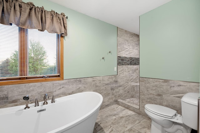2703 10th Ave SW, Austin, MN 55912 - bathroom featuring tile walls, a freestanding tub, toilet, a tile shower, and wainscoting