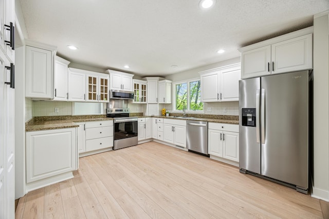 1588 Chatham Ave, Arden Hills, MN 55112 - kitchen with stainless steel appliances, light wood-style floors, backsplash, white cabinets, and a sink