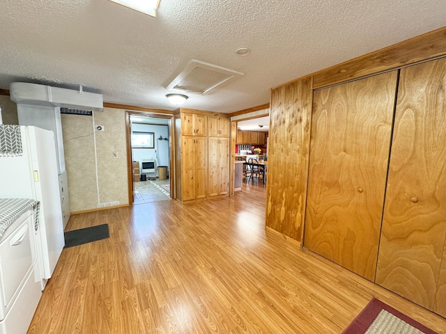 hallway with attic access, a textured ceiling, light wood finished floors, and baseboards