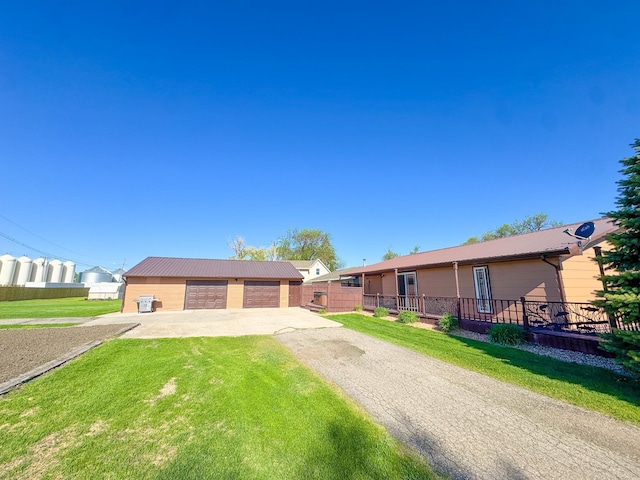 single story home with a detached garage, an outbuilding, and metal roof