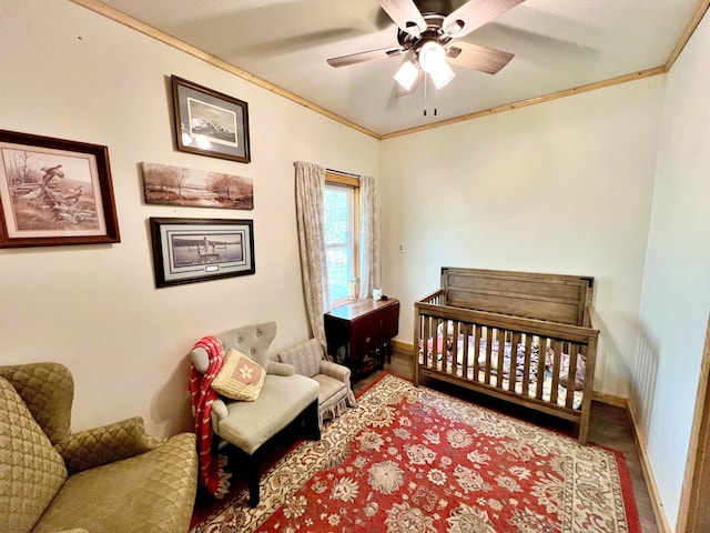 bedroom with crown molding, baseboards, ceiling fan, and a crib