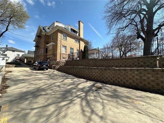 215 5th St S, Montevideo, MN 56265 - view of home's exterior featuring fence, a chimney, and brick siding
