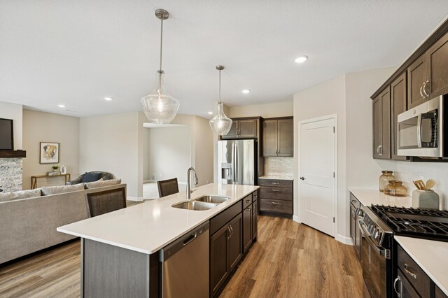 1419 Victory Ln NE, Isanti, MN 55040 - kitchen with stainless steel appliances, a sink, open floor plan, dark brown cabinetry, and recessed lighting