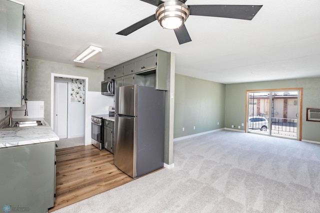 kitchen with stainless steel appliances, a sink, a ceiling fan, and baseboards