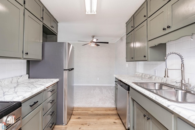 kitchen featuring a sink, a ceiling fan, stainless steel appliances, gray cabinets, and backsplash