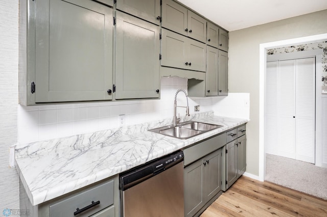kitchen featuring stainless steel dishwasher, a sink, gray cabinetry, tasteful backsplash, and light wood finished floors