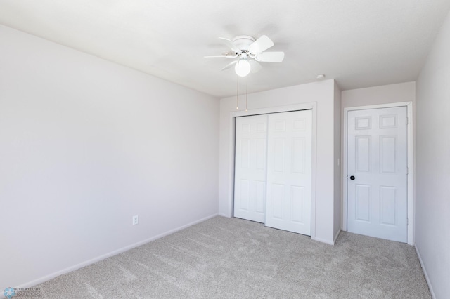 unfurnished bedroom with light colored carpet, a closet, baseboards, and ceiling fan