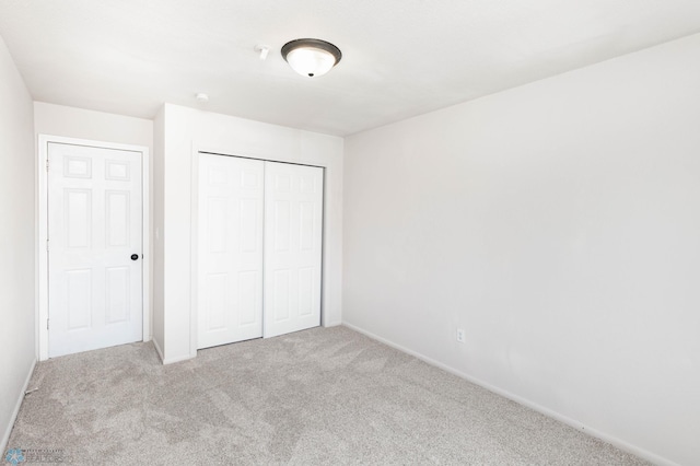 unfurnished bedroom with carpet floors, a closet, and baseboards