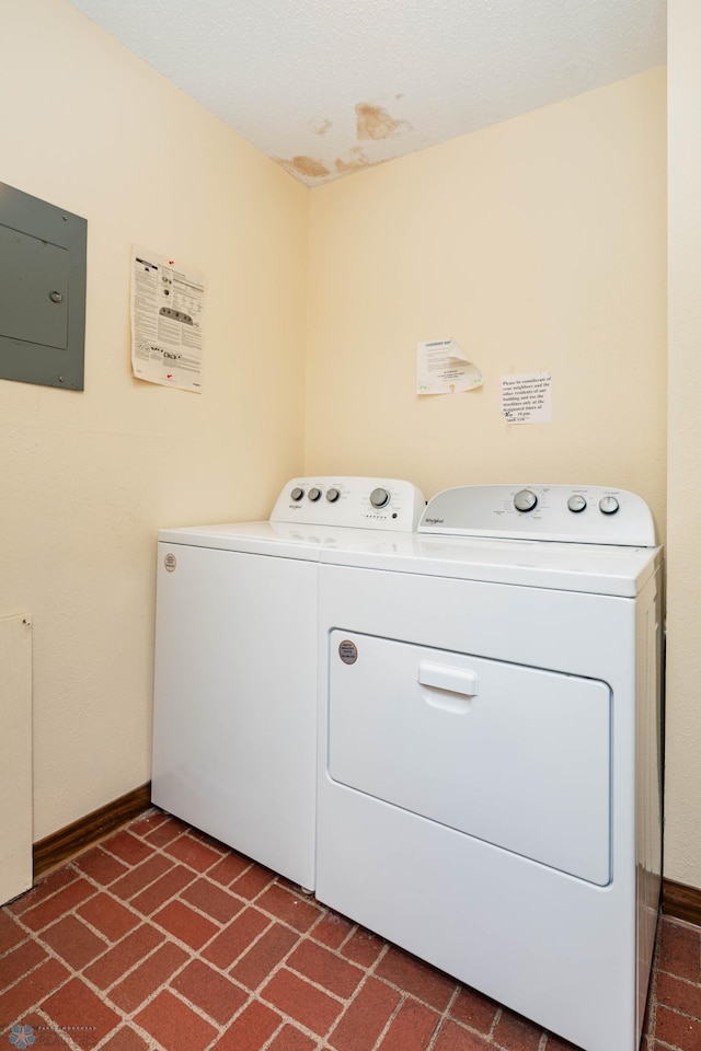 clothes washing area featuring washer and dryer, brick patterned floors, and baseboards