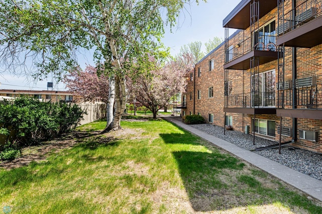 view of green lawn featuring a balcony