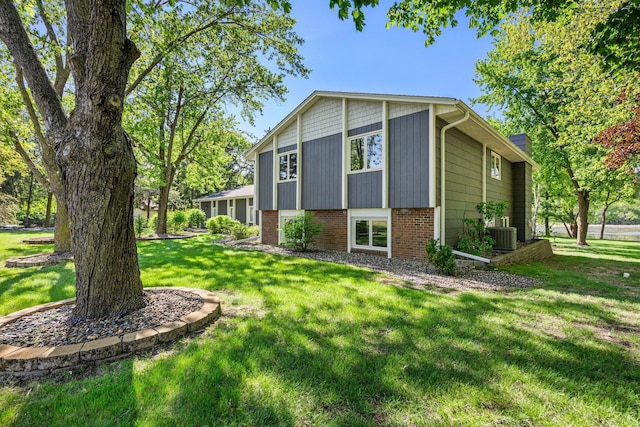 view of home's exterior featuring a lawn, brick siding, and central AC