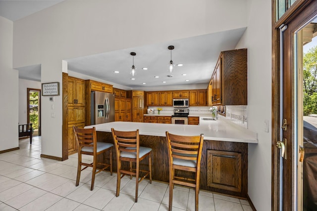 kitchen featuring appliances with stainless steel finishes, a sink, a peninsula, light countertops, and light tile patterned floors