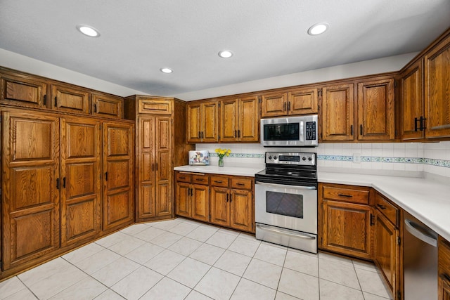 kitchen with stainless steel appliances, light countertops, brown cabinets, recessed lighting, and decorative backsplash