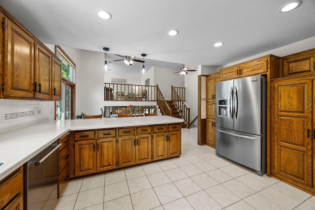 kitchen with appliances with stainless steel finishes, a ceiling fan, a peninsula, brown cabinets, and recessed lighting