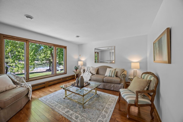 living area featuring baseboard heating, baseboards, wood-type flooring, and a textured ceiling