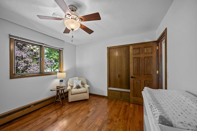 bedroom featuring wood finished floors, a textured ceiling, baseboards, and a ceiling fan