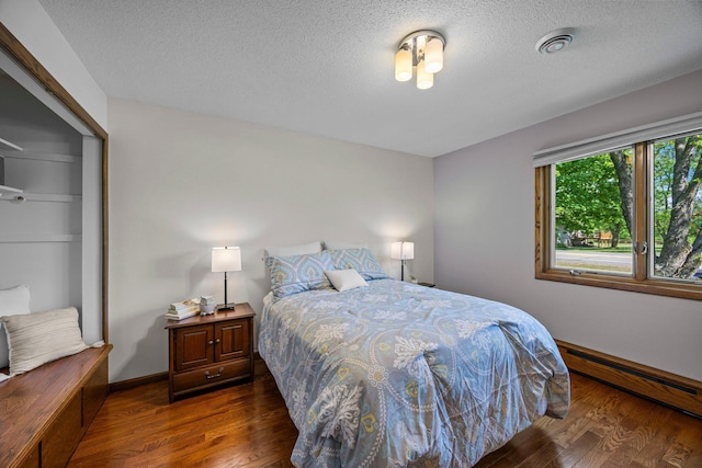 bedroom with wood finished floors, a baseboard radiator, a textured ceiling, and a closet