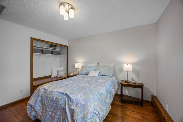 bedroom with wood finished floors, a closet, baseboards, and a textured ceiling
