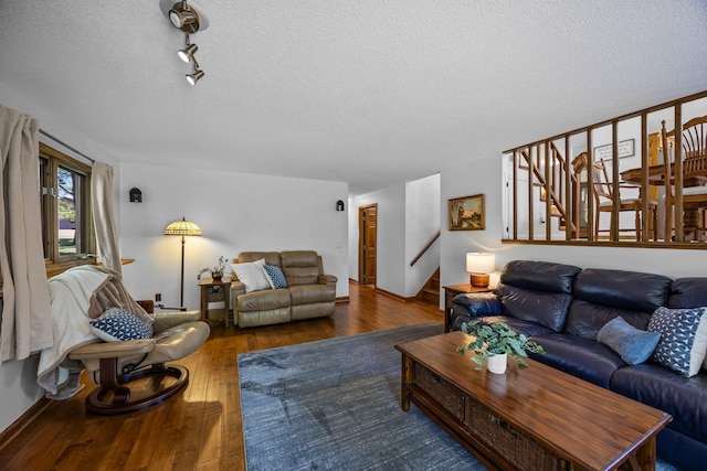 living room featuring stairway, hardwood / wood-style flooring, a textured ceiling, and baseboards