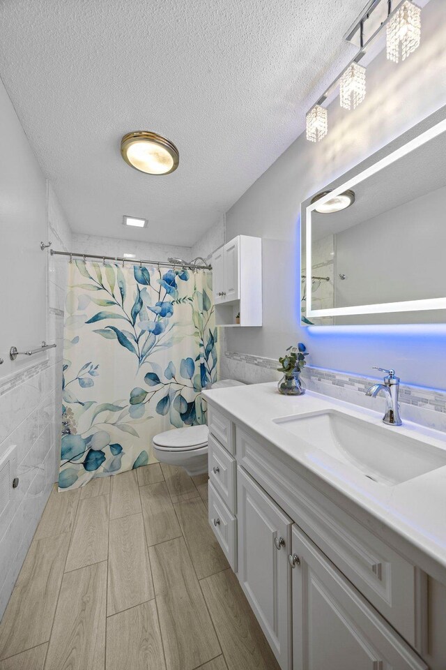 full bathroom featuring toilet, vanity, curtained shower, a textured ceiling, and wood finish floors