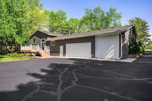 view of front of property with a wooden deck, roof with shingles, and an attached garage
