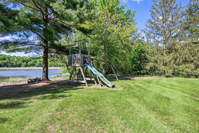 view of jungle gym featuring a yard, a forest view, and a water view