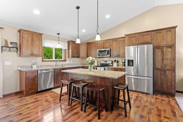 805 Cologne Ln, Waverly, MN 55390 - kitchen with stainless steel appliances, lofted ceiling, wood finished floors, a kitchen island, and a breakfast bar
