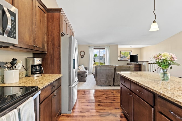 805 Cologne Ln, Waverly, MN 55390 - kitchen featuring appliances with stainless steel finishes, dark wood finished floors, light stone counters, pendant lighting, and open floor plan