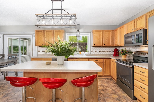 5921 200th St W, Farmington, MN 55024 - kitchen featuring appliances with stainless steel finishes, decorative backsplash, a textured ceiling, light countertops, and a center island